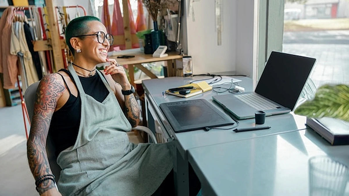 Female worker uses graphics tablet and laptop for retouching photos or digital drawing in studio